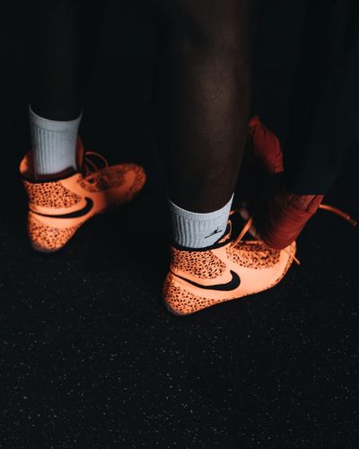 Close-up on athletic shoes on a dark floor, symbolizing readiness.